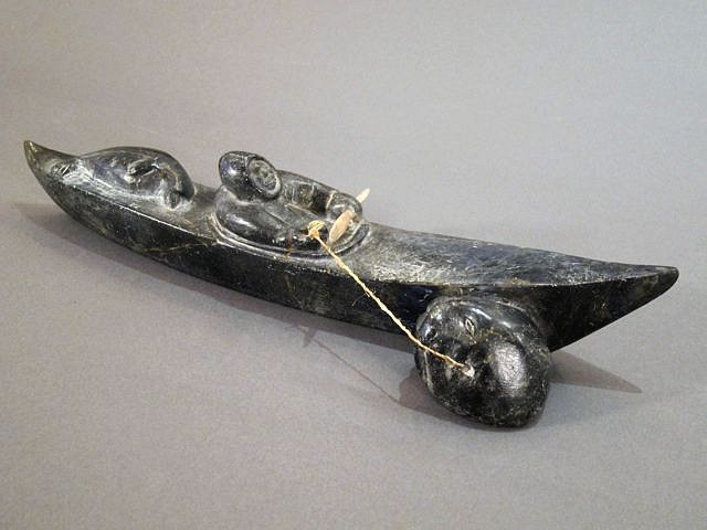 Noah Nowrakudluk, Hunter in kayak with seal and walrus head, c. 1960-1969
Stone, 2 3/4 x 13 x 3 1/2 in. (7 x 33 x 8.9 cm)
A classic Arctic Quebec piece, showing a hunter who had a very good day -- there is a seal on the kayak deck, and a walrus being towed in the water alongside.
00209-1