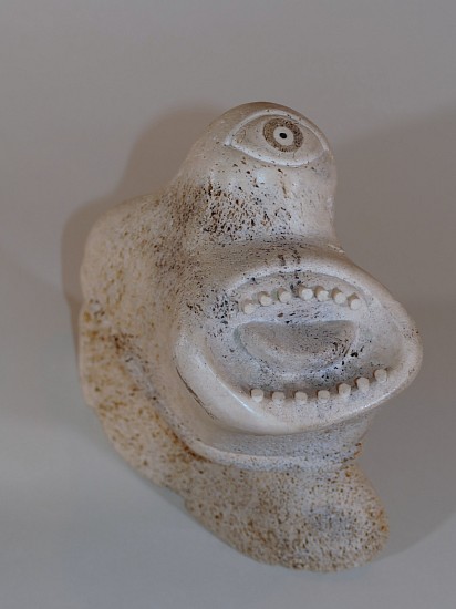 Karoo Ashevak, Cyclops figure, c. 1965
Whalebone, 9 3/4 x 9 x 4 in.
This arresting sculpture is an early work by Karoo Ashevak. Its only distinct features are a single eye and a large, toothy, open mouth, both carefully detailed.  The sculpture is signed in syllabics, confirming a viewer's immediate impression that the work is by Karoo.  Presumably it depicts a spirit.  
03540-1