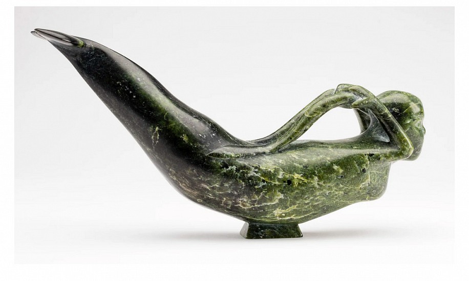 Osuituk Ipeelee, Sedna, 1983
5 3/4 x 11 3/4 x 3 in.
Osuitok Ipeelee was the finest and most versatile of the first generation Cape Dorset carvers.  It is well known that Osuitok was a great admirer of the female form; among his favourite subjects were young women engaged in a variety of pursuits: fishing, performing chores, and even playing a concertina. In comparison his depictions of the Inuit sea goddess are relatively few, which is surprising given that many other Inuit artists have carved Sedna as a creature with beautiful female attributes. There is however one depiction by Osuitok that is quite similar, a contemporaneous version in light green stone that graced the cover of Alma Houstonâ€™s book Inuit Art: An Anthology [1]. Although some of the details differ, the two sculptures are similar in size, pose, and overall look.

Osuitokâ€™s Sea Goddess has the look of a European-style mermaid with a human head, arms and breasts, and a beluga-like lower body. Beautifully balanced on a small base, her gracefully arched body performs a seal-like balletic swoop, while her hands grasp long braids that seem to transform into fronds of seaweed.


1. Alma Houstonâ€™s anthology also contains the article â€œOsuitok Ipeeleeâ€ by Jean Blodgett which illustrates the sculpture on page 53.


References: For a similarly posed and styled depiction of the sea goddess by Osuitok from 1983, see Jean Blodgett, â€œOsuitok Ipeeleeâ€ in Alma Houston, ed., Inuit Art: An Anthology, (Winnipeg, Watson & Dwyer, 1987), p. 53 and front cover.
03548-1